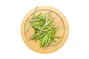 Lot of pieces of fresh evergreen sprig of rosemary on bamboo plate flatlay isolated on white background