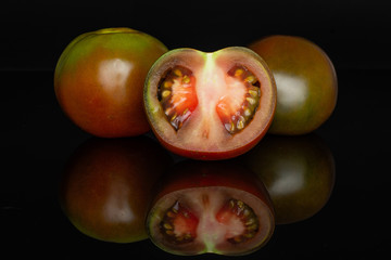 Group of two whole one half of fresh greenish red tomato isolated on black glass