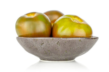 Group of three whole fresh greenish red tomato on grey ceramic plate isolated on white background