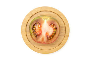 One half of fresh greenish red tomato on bamboo plate flatlay isolated on white background