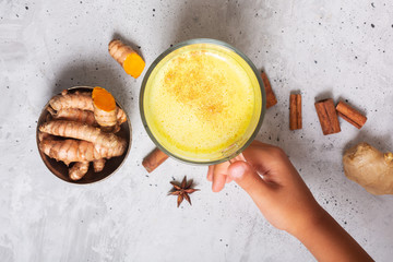 Golden turmeric milk on the gray background with ingredients