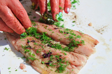 Woman sprinkles fish with spices. Close-up. Background.