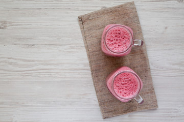 Raspberry smoothie in glass jar mugs, overhead view. Flat lay, from above, top view. Copy space.