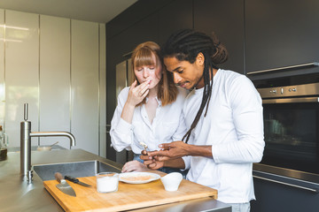 Obraz premium Mixed Race Couple Preparing Food Together in the Kitchen.