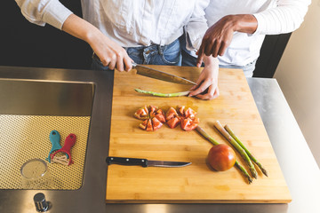 Mixed Race Couple Cutting Vegetable on Cutting Board in the Kitchen.