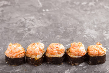 Japanese maki sushi rolls with flying fish roe, cheese on black concrete background. Side view.