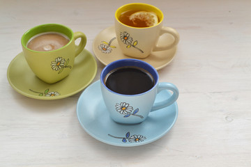 Coffee, cappuccino and Tea in colorful cups  on shabby table