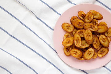 Homemade fried plantains on a pink plate, top view. Overhead, from above, flat lay. Copy space.