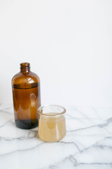 Amber Glass and Cup of Kombucha, Healthy Probiotic Drink, White and Marble Background, Copy Space