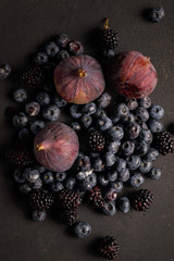Blueberries, figs and blackberries on a black table. Country style.