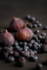 Fototapeta premium Blueberries, figs and blackberries on a black table. Country style.