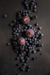 Blueberries, figs and blackberries on a black table. Country style. Top view.