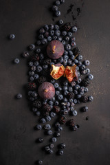 Blueberries, figs and blackberries on a black table. Country style. Top view.