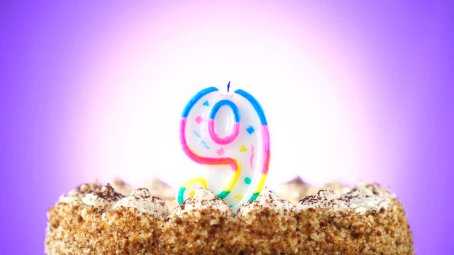 Birthday cake with a burning birthday candle. Number 9. Background changes color