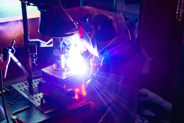 Industrial production. Welding business. Welder at work. The workplace of the welder. Man welding metal parts. Protection of the worker when performing welding operations.