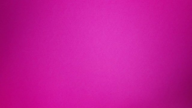 A wine glass rolling up, on and off the screen, top down view on a hot pink background.