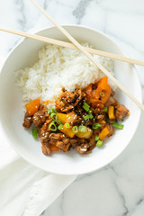 Sweet and Sour Ground Pork with Yellow and Orange Bell Peppers and Steamed Rice topped with Green Onions, Marble Background
