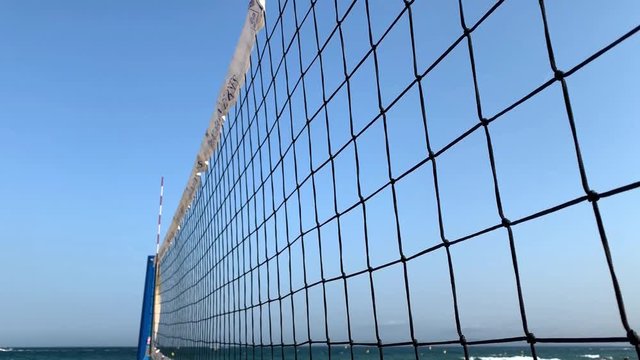 Beach volley net. View through the volleyball net on the cityscape, sea and blue sky. Summer sport concept, enjoy perfect vacation. Volleyball on the beach, sport competition.