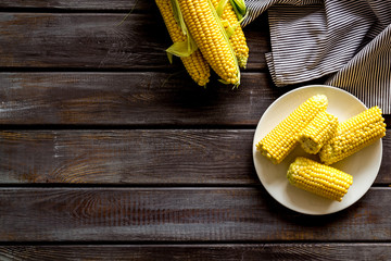 Corn on cobs and on plate on wooden background top view copyspace