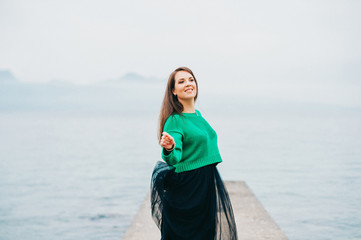 Outdoor portrait of beautiful woman wearing green pullover, black skirt