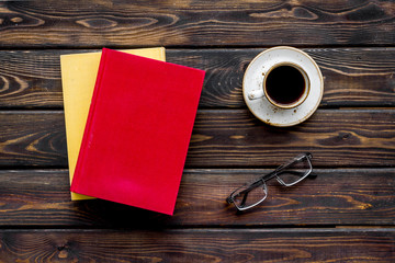 Books on library desk for reading, coffee, glasses on wooden background top view
