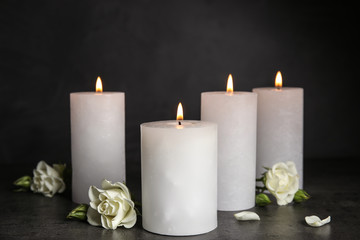 Burning candles and beautiful flowers on grey table