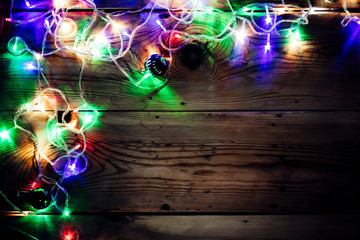 Christmas decorative lights. Christmas garland lights on wood. Colorful Xmas light bulbs on rustic brown plank