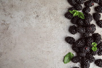 Tasty ripe blackberries with mint on grey table, flat lay. Space for text