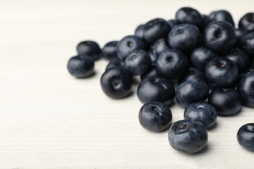 Fresh acai berries on white wooden table, closeup view. Space for text