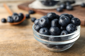 Bowl of fresh acai berries on wooden table, closeup view. Space for text