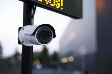 Modern CCTV security camera on street, closeup. Space for text