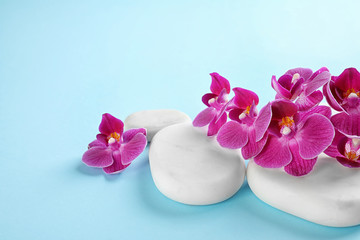 Fototapeta na wymiar Orchid with white spa stones on light blue background