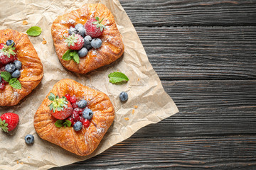 Fresh delicious puff pastry with sweet berries on dark wooden background, top view. Space for text