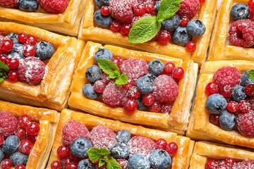 Fresh delicious puff pastry with sweet berries as background, top view