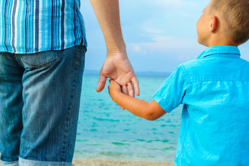hands of happy parent and child at sea greece background