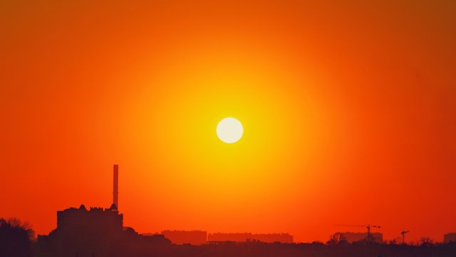 Heatwave hot sun. Global warming llimate change. Summer background with a magnificent summer sun. Autumn sunset. The setting sun in a clear sky. Hot city weather concept. High temperature at summer.