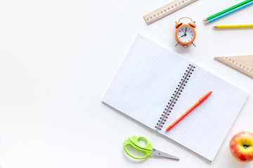 Back to school with stationary, notebook and alarm clock on white student desk background top view mock-up