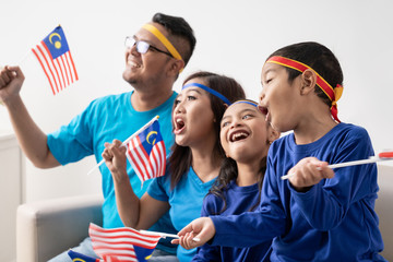 Obraz premium excited malaysian sport fans supporter. asian family with malaysia flag
