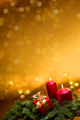 Gifts with bows, burning red candles and spruce branch on a golden background.