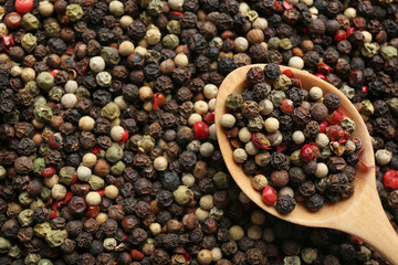 Closeup of wooden spoon with mixed peppercorns, top view