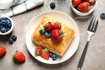 Fresh delicious puff pastry with sweet berries on grey marble table, flat lay