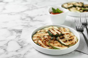 Grilled zucchini slices served on white marble table. Space for text