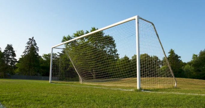 Low angle shot of a soccer net and field on a sunny, summer morning