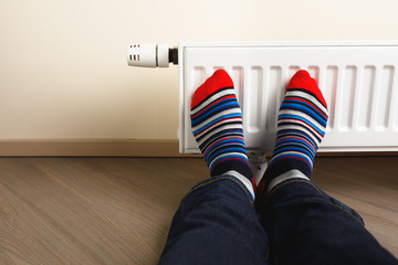 legs with colorful socks in front of heating radiator