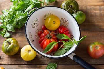 Ripe tomatoes of different colors in the old colander. Close up.