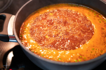 pumpkin tomato peas soup boiling in the pot on the stove