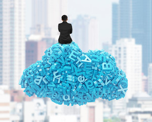 Big data and cloud computing concept. Rear view of businessman sitting on cloud of blue letters and numbers, on city buildings cityscape background.