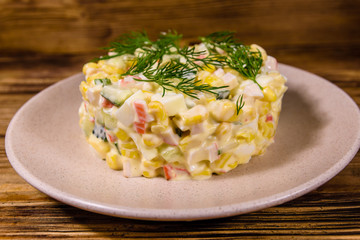 Salad with crab sticks, boiled eggs and cucumbers on a ceramic plate