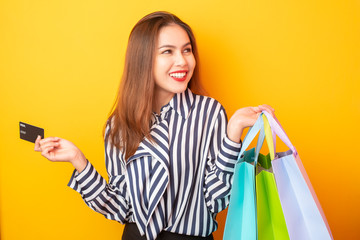 Happy shopping woman on yellow background