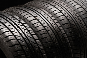 Four old used summer tires. Close-up on a black background.